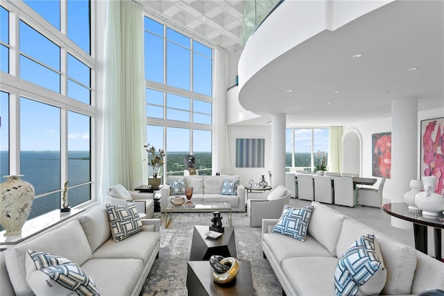 carpeted living room with a water view and a towering ceiling