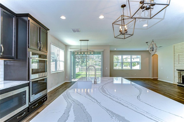 kitchen featuring light stone counters, appliances with stainless steel finishes, and hanging light fixtures