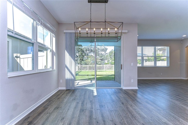 unfurnished dining area with a notable chandelier and dark hardwood / wood-style floors