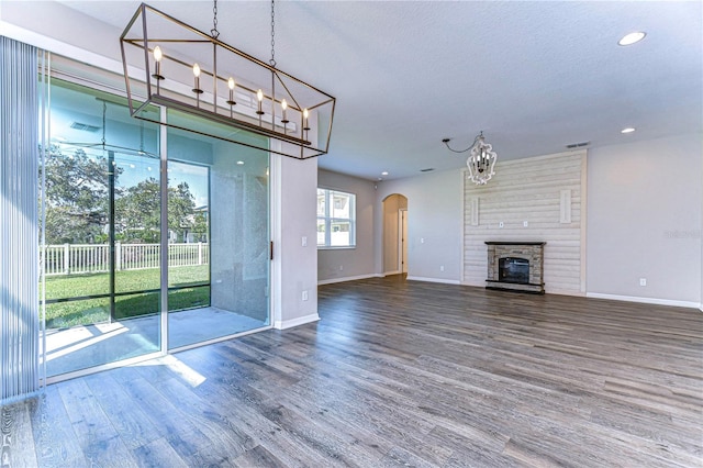 unfurnished living room with a textured ceiling, hardwood / wood-style flooring, and a large fireplace