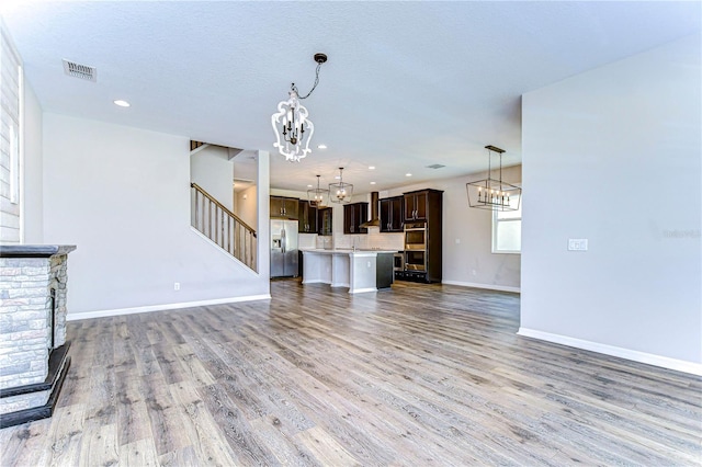 unfurnished living room featuring a fireplace, a textured ceiling, and light wood-type flooring