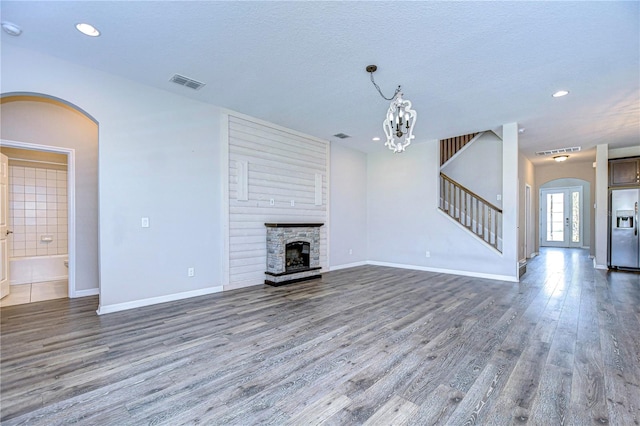 unfurnished living room with a stone fireplace, hardwood / wood-style floors, and a textured ceiling