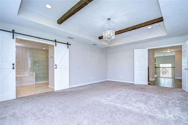 unfurnished bedroom with beamed ceiling, ensuite bath, a barn door, a raised ceiling, and carpet flooring