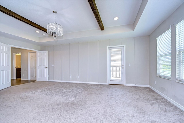 spare room featuring beam ceiling, carpet flooring, and a chandelier