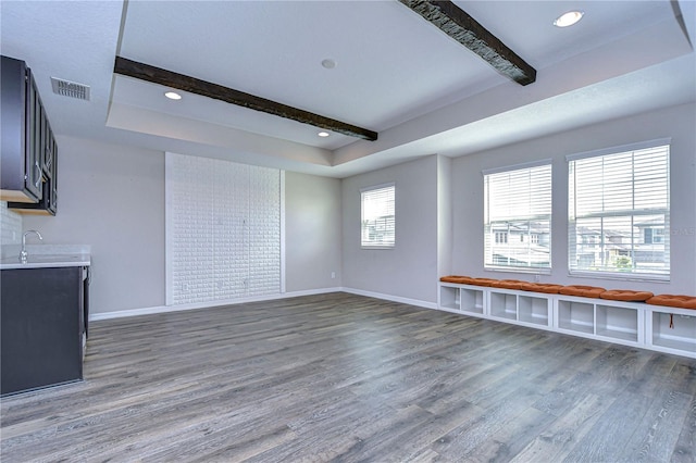 unfurnished living room with beamed ceiling, dark wood-type flooring, and a raised ceiling