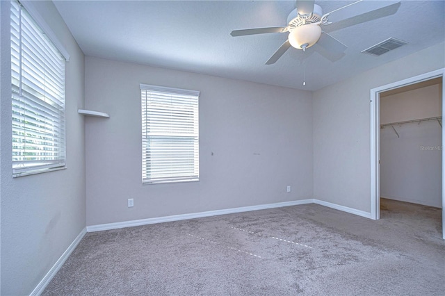 unfurnished bedroom with multiple windows, light colored carpet, and ceiling fan