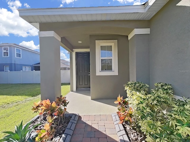 view of exterior entry featuring a lawn