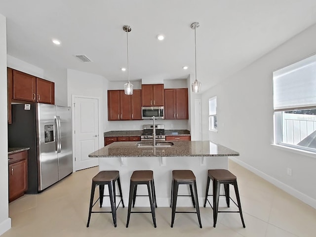 kitchen featuring a center island with sink, sink, hanging light fixtures, and appliances with stainless steel finishes