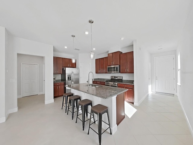 kitchen with a kitchen bar, appliances with stainless steel finishes, a kitchen island with sink, sink, and pendant lighting