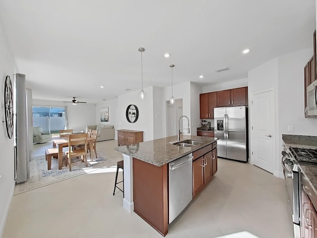 kitchen with ceiling fan, sink, hanging light fixtures, a center island with sink, and appliances with stainless steel finishes