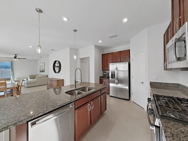 kitchen with appliances with stainless steel finishes, dark stone counters, ceiling fan, sink, and hanging light fixtures