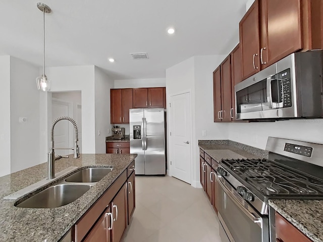 kitchen featuring dark stone counters, sink, light tile patterned floors, decorative light fixtures, and stainless steel appliances