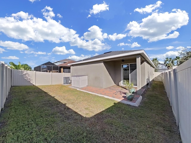 rear view of property featuring a yard, a patio, and central air condition unit