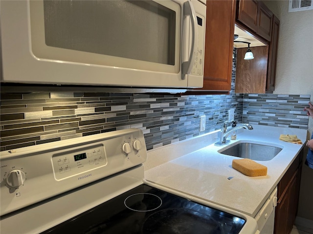 kitchen featuring sink, backsplash, and white appliances