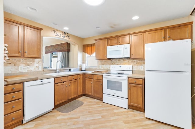 kitchen featuring light hardwood / wood-style floors, sink, backsplash, and white appliances