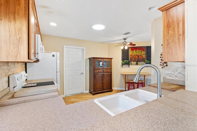 kitchen featuring ceiling fan, sink, light wood-type flooring, and stove