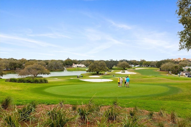 view of property's community with a water view and a lawn