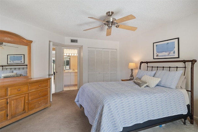 2571 Cyprus Dr Unit 1-202, Palm Harbor, FL 34684 - bedroom with light colored carpet, a closet, ensuite bath, a ceiling fan, and a textured ceiling