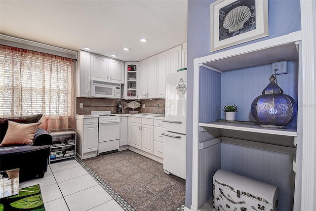 kitchen with sink, light tile patterned floors, white cabinetry, white appliances, and tasteful backsplash