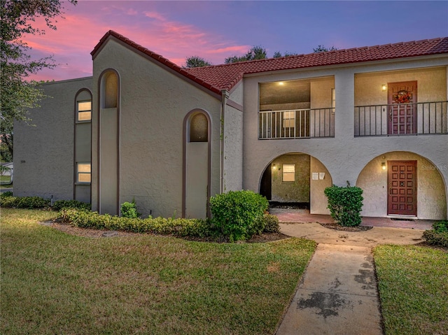 mediterranean / spanish-style house with a balcony and a lawn