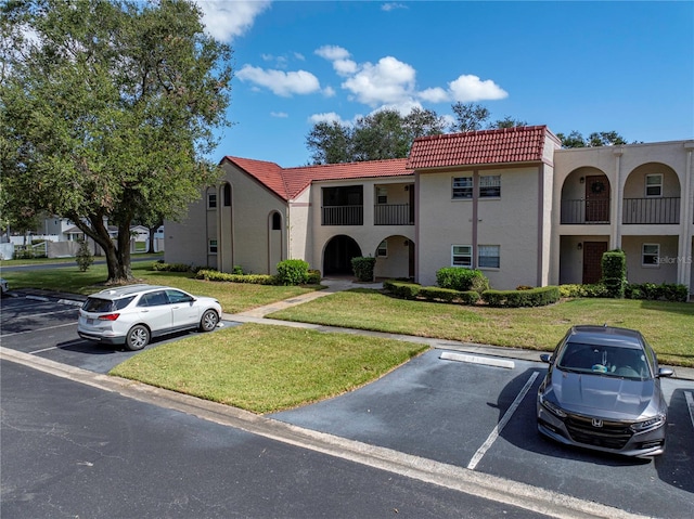 view of front facade featuring a front lawn and a balcony