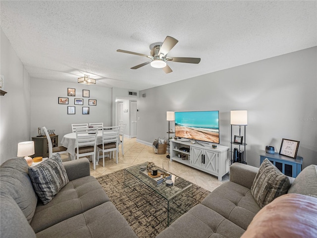 living room with a textured ceiling, ceiling fan, and light tile patterned floors