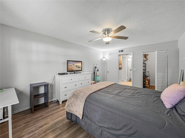 bedroom with dark wood-type flooring, a closet, a textured ceiling, and ceiling fan