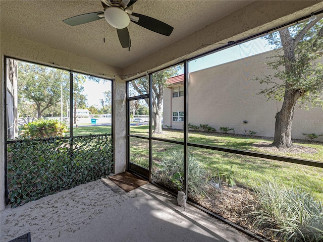 unfurnished sunroom featuring ceiling fan and plenty of natural light