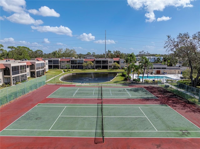 view of tennis court featuring a water view and a community pool