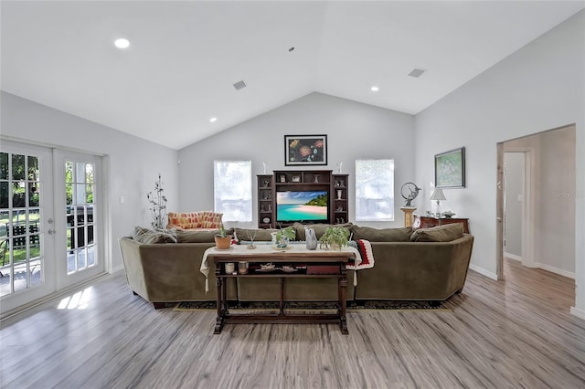 living room with french doors, light hardwood / wood-style flooring, vaulted ceiling, and a wealth of natural light