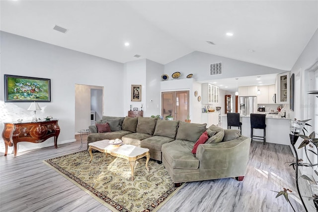 living room with light hardwood / wood-style floors and high vaulted ceiling