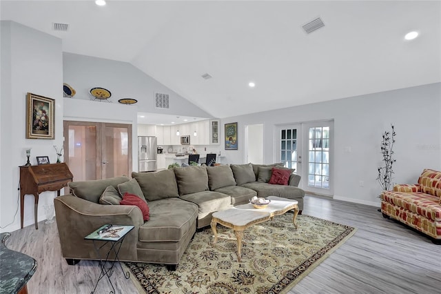 living room with french doors, light hardwood / wood-style flooring, and high vaulted ceiling