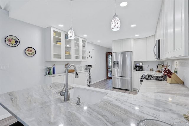 kitchen featuring light hardwood / wood-style flooring, hanging light fixtures, stainless steel appliances, sink, and white cabinets