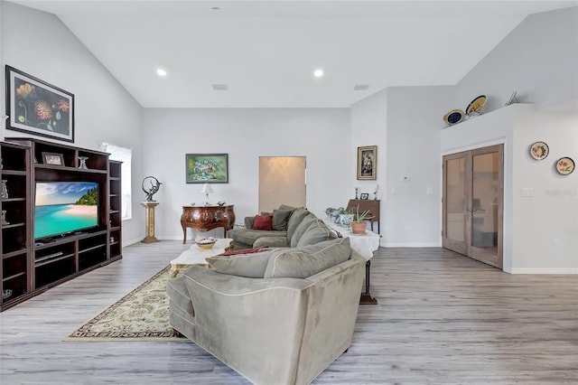 living room featuring french doors, vaulted ceiling, and light hardwood / wood-style flooring