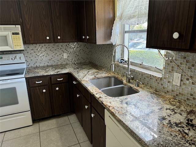 kitchen with light stone counters, tasteful backsplash, sink, and white appliances