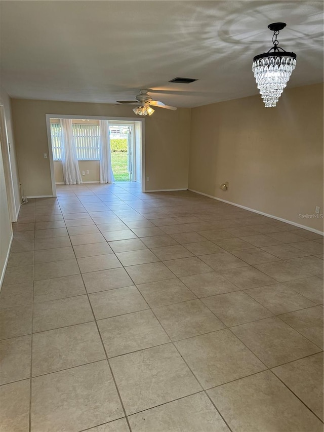 empty room with light tile patterned floors and ceiling fan with notable chandelier