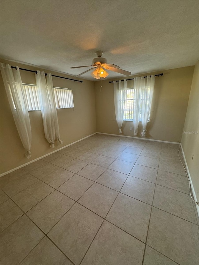 empty room with a textured ceiling, light tile patterned floors, and ceiling fan