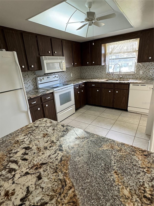 kitchen with light tile patterned flooring, dark brown cabinets, sink, white appliances, and ceiling fan