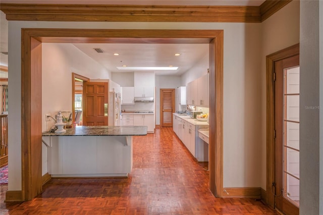 kitchen featuring kitchen peninsula, white cabinets, dark parquet flooring, sink, and white refrigerator