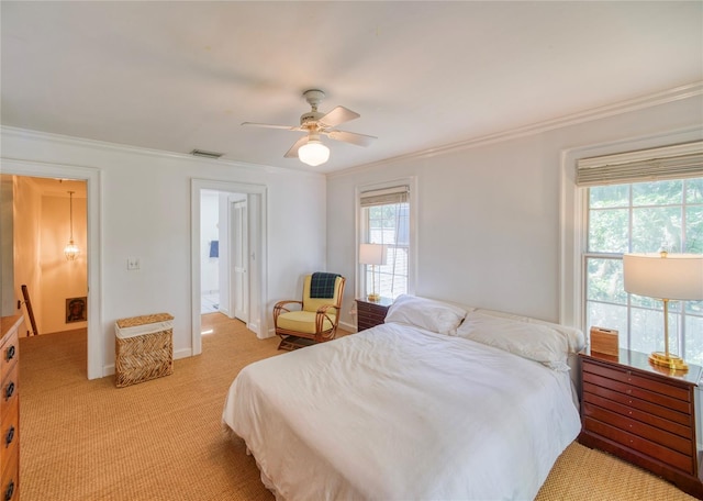 bedroom with ceiling fan, light carpet, ornamental molding, and ensuite bath