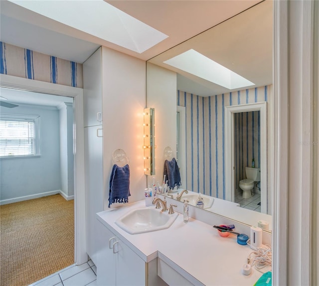 bathroom with vanity, tile patterned flooring, toilet, and a skylight