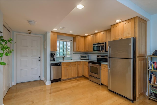 kitchen with stainless steel appliances, light brown cabinetry, sink, light hardwood / wood-style flooring, and backsplash