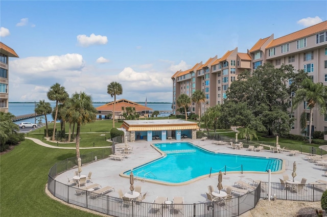 view of swimming pool with a patio, a water view, and a lawn