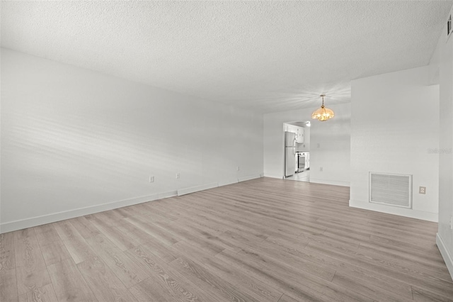 unfurnished living room featuring a textured ceiling and light wood-type flooring