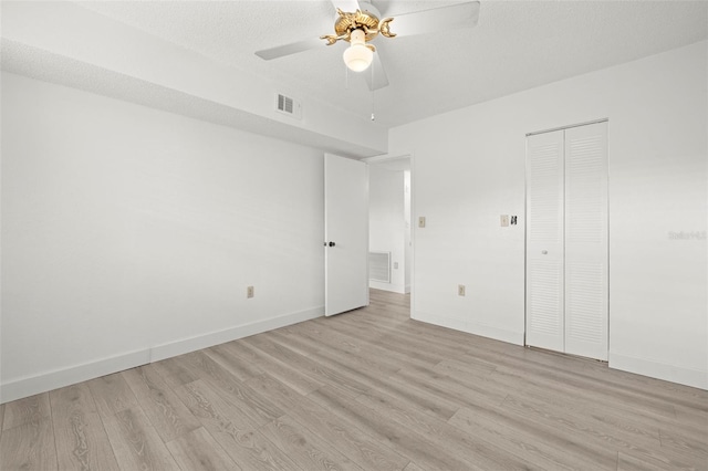 unfurnished bedroom with ceiling fan, a closet, a textured ceiling, and light wood-type flooring