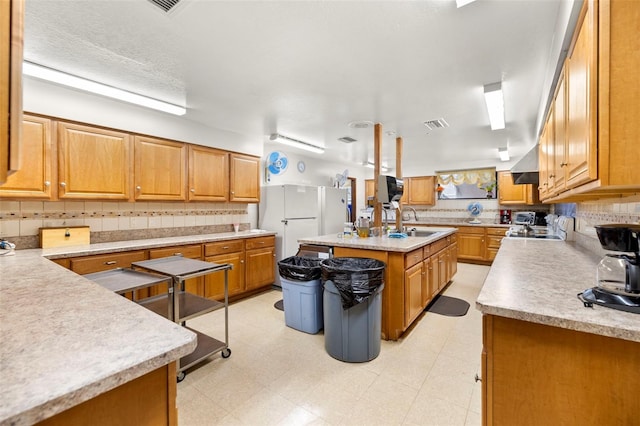 kitchen featuring backsplash, sink, and a kitchen island with sink