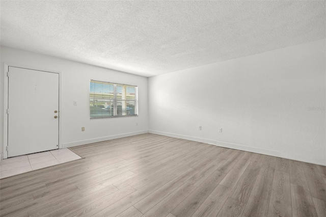 empty room featuring a textured ceiling and light hardwood / wood-style flooring