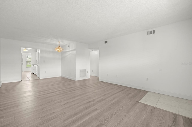 unfurnished living room featuring light hardwood / wood-style floors and a textured ceiling