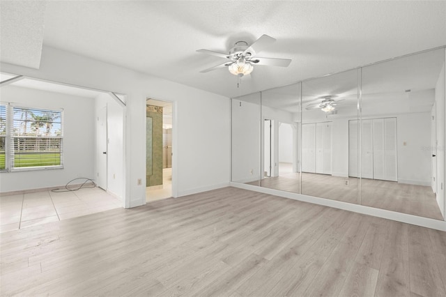 empty room with ceiling fan, light wood-type flooring, and a textured ceiling