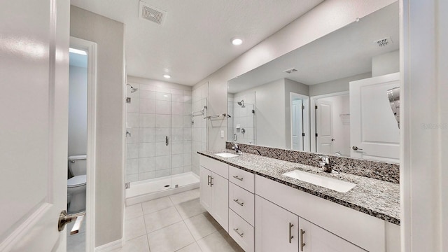 bathroom featuring vanity, toilet, tiled shower, and tile patterned flooring